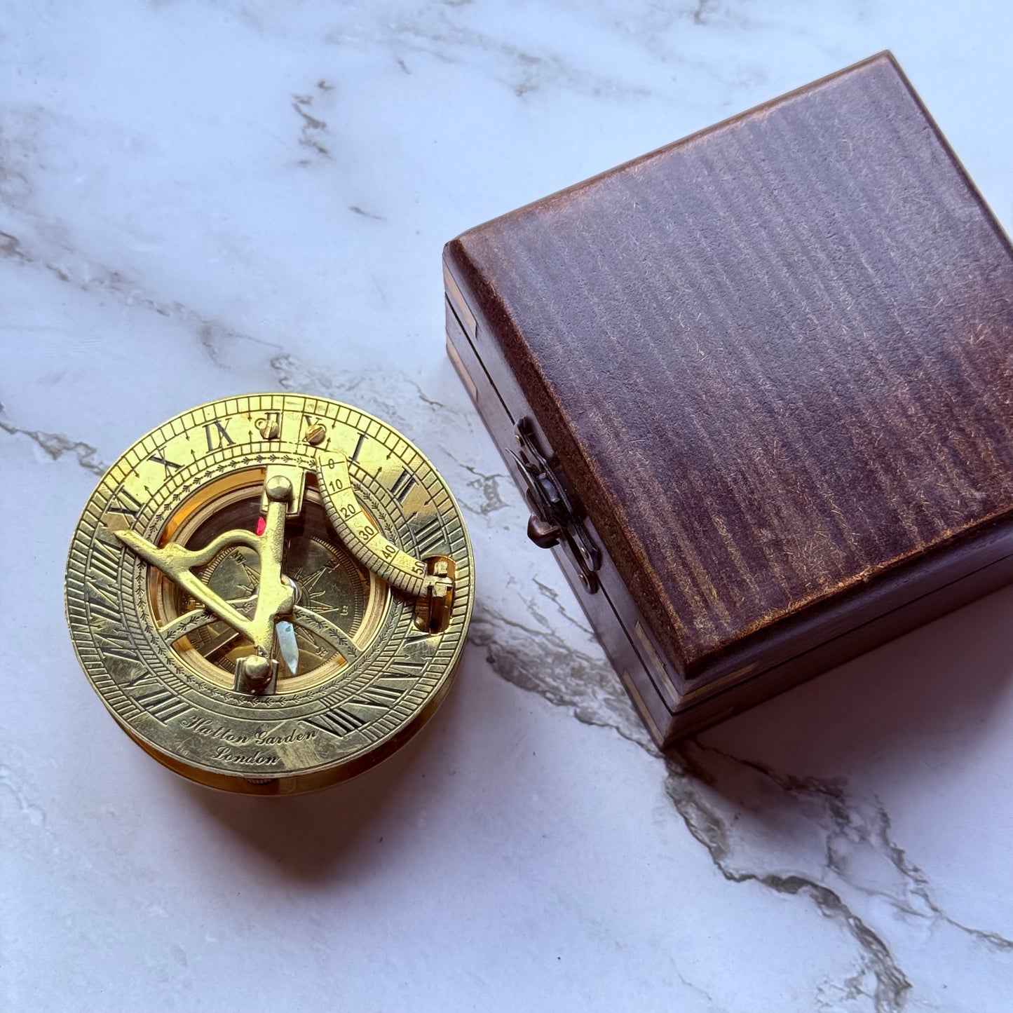 Brass compass and wooden box on a marble surface