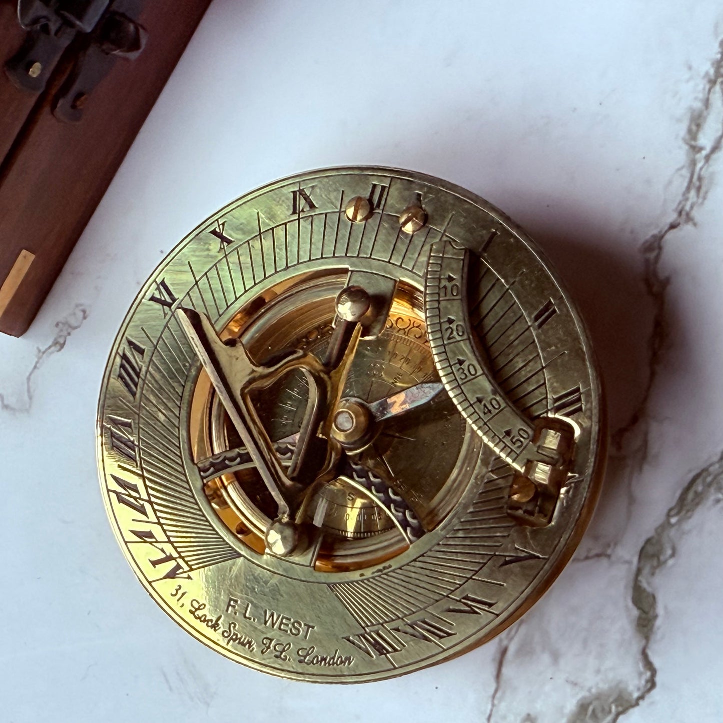 Brass sundial compass on a marble surface