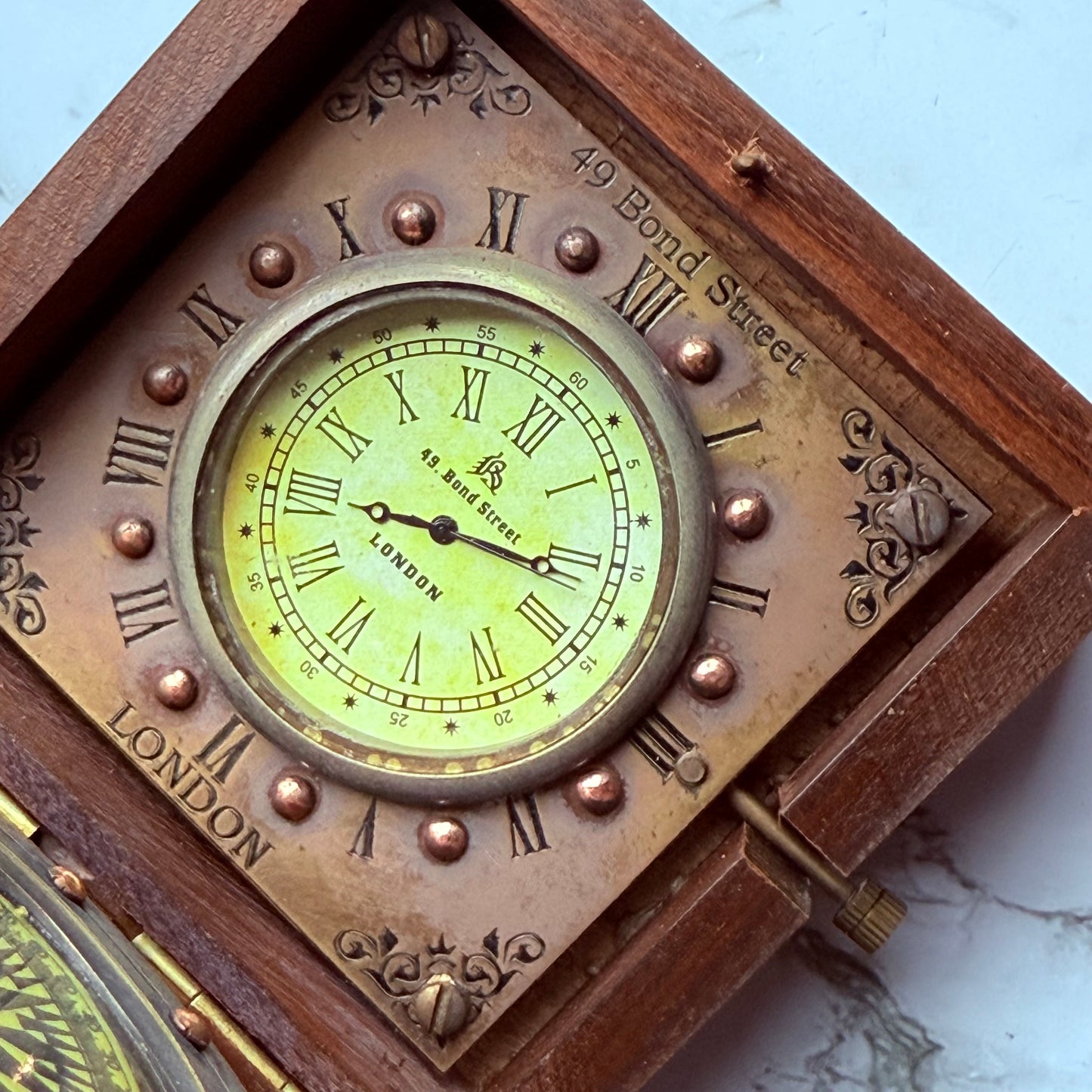 Vintage-style clock with Roman numerals and wooden frame on a marble surface