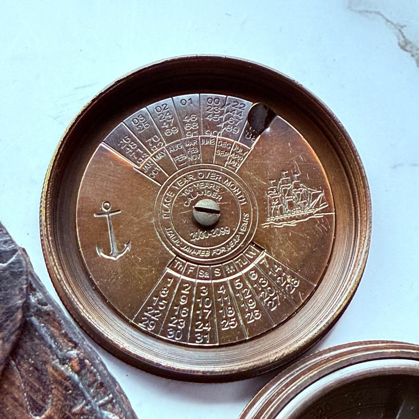 Close-up of a bronze compass with engravings on a light blue background