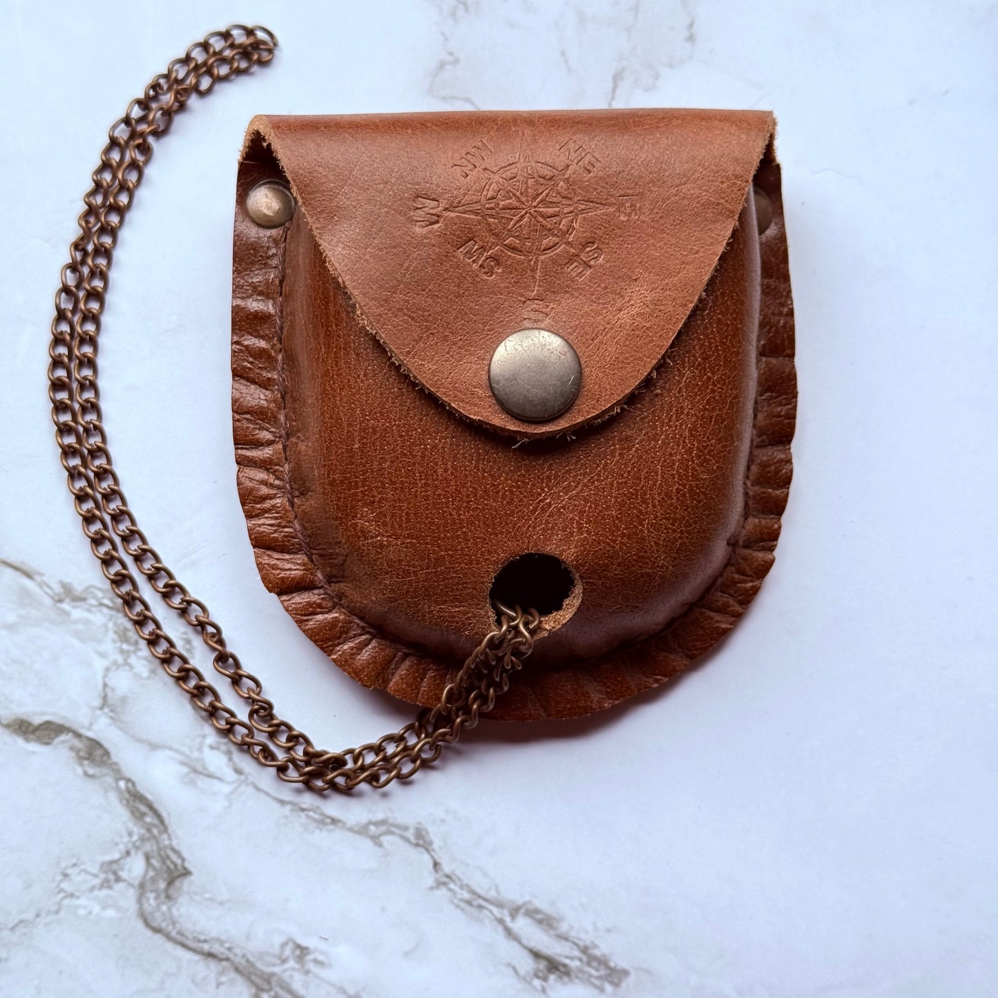 Brown leather pouch with chain on a marble surface