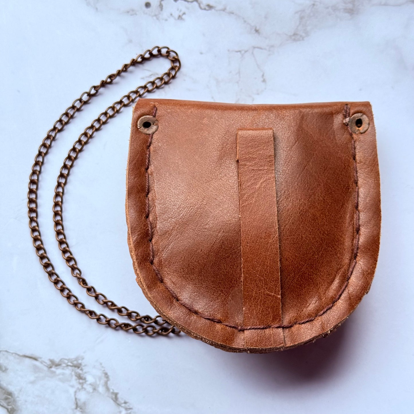 Brown leather pouch with chain on a marble surface