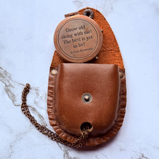 Brown leather pouch with chain and engraved quote on a marble surface