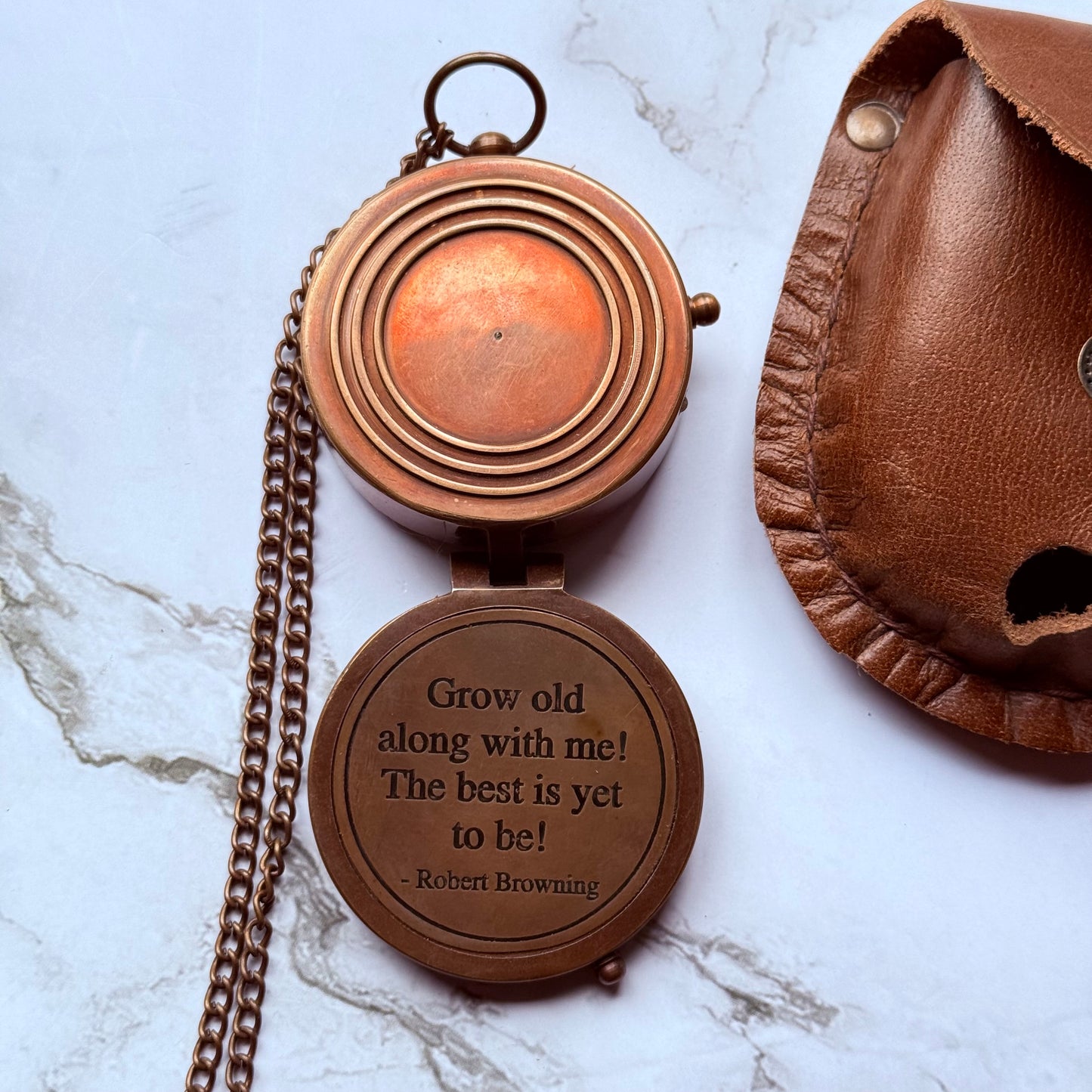 Bronze pocket compass with engraved quote on a marble surface