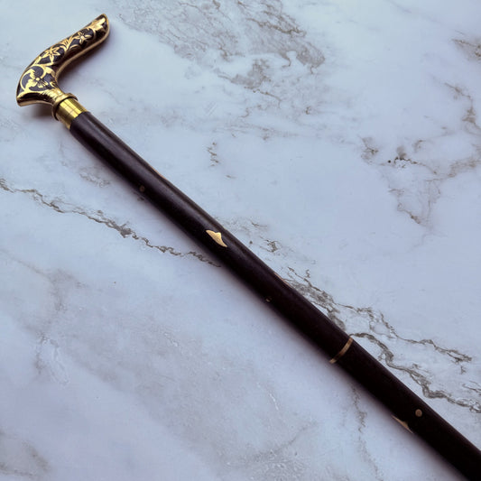 Decorative walking cane handle with brass floral patterns and brass inlay design on the shaft