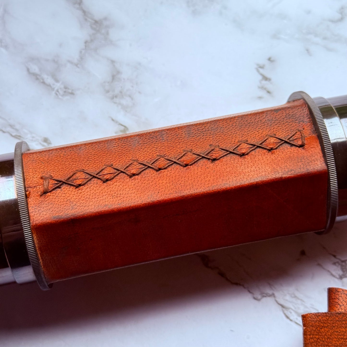 Close photo showing the leather-wrapped spyglass with intricate stitching