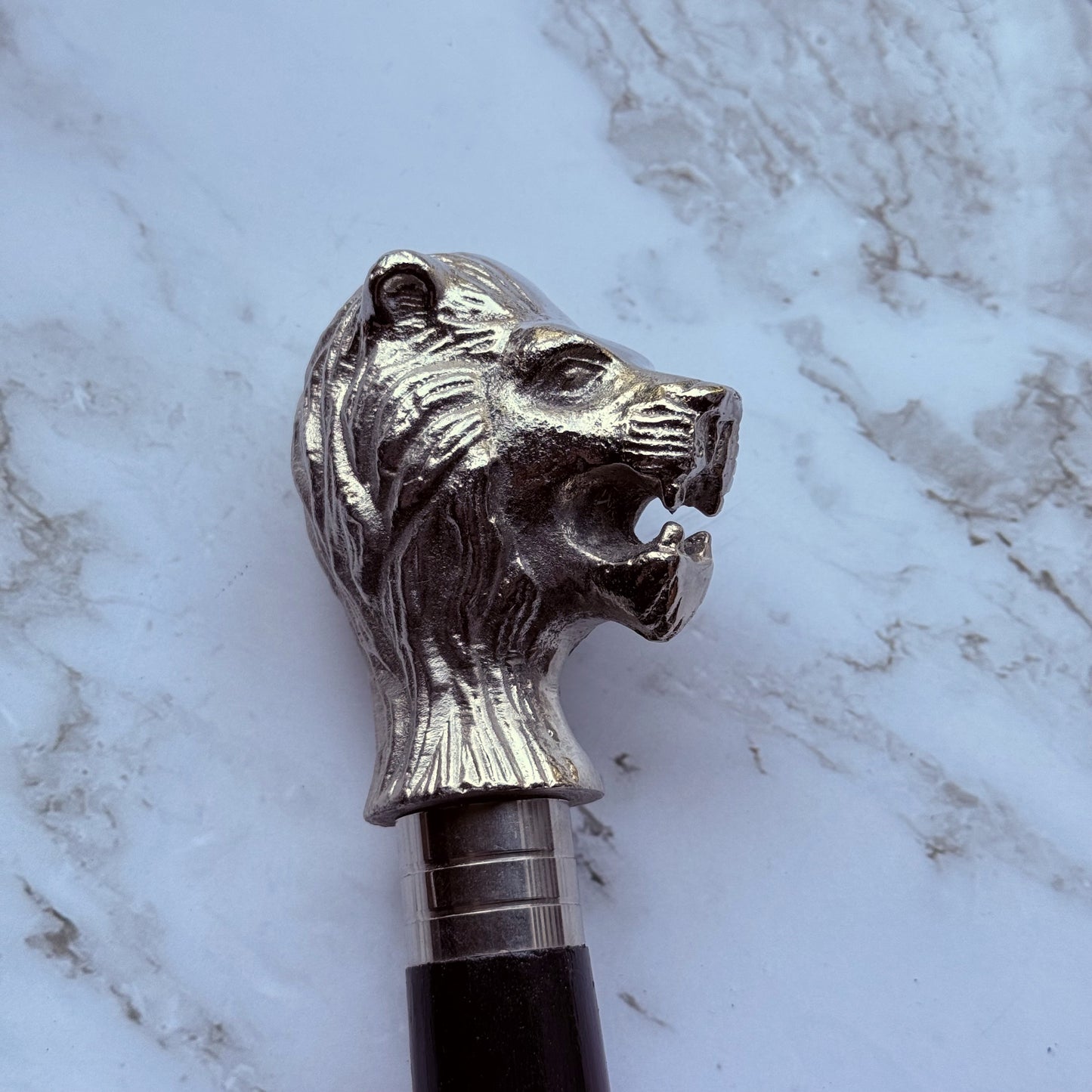 Detailed profile photo of the metal lion shaped handle of the cane