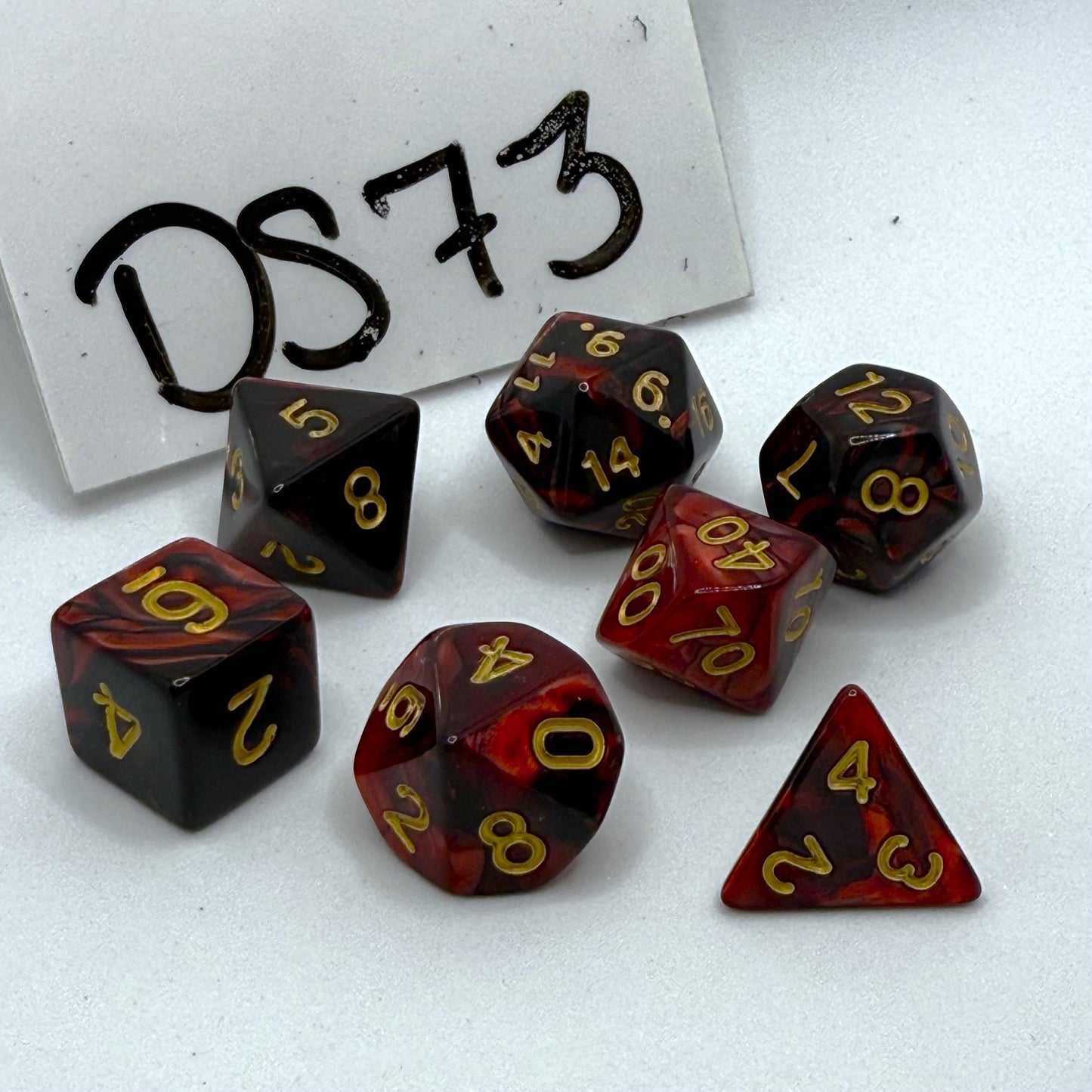 Set of polyhedral dice with red and black marbled pattern on a white background