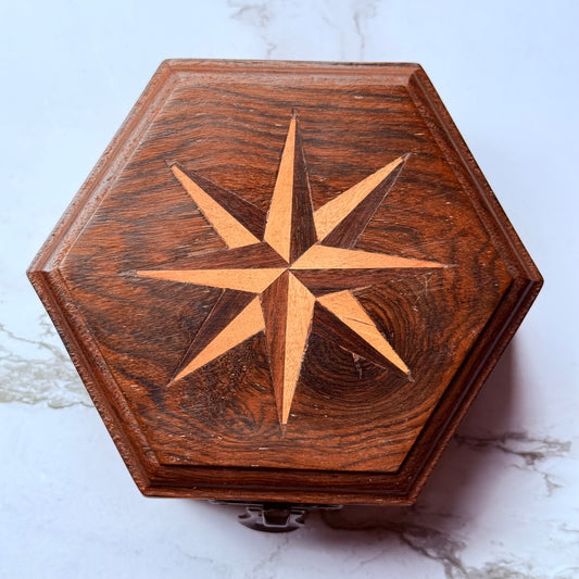 Wooden hexagonal box with star design on a marble surface