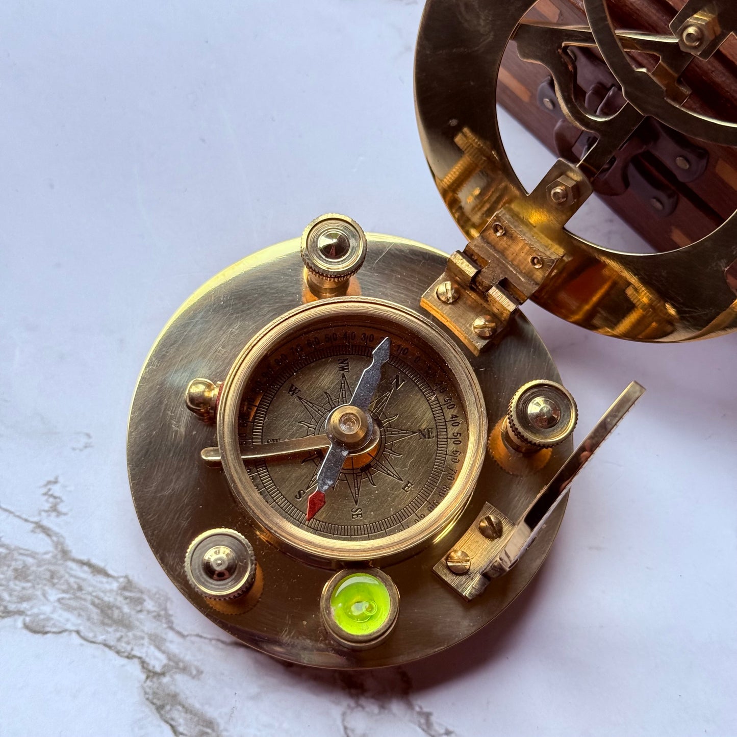 Brass compass with mechanical components on a marble surface
