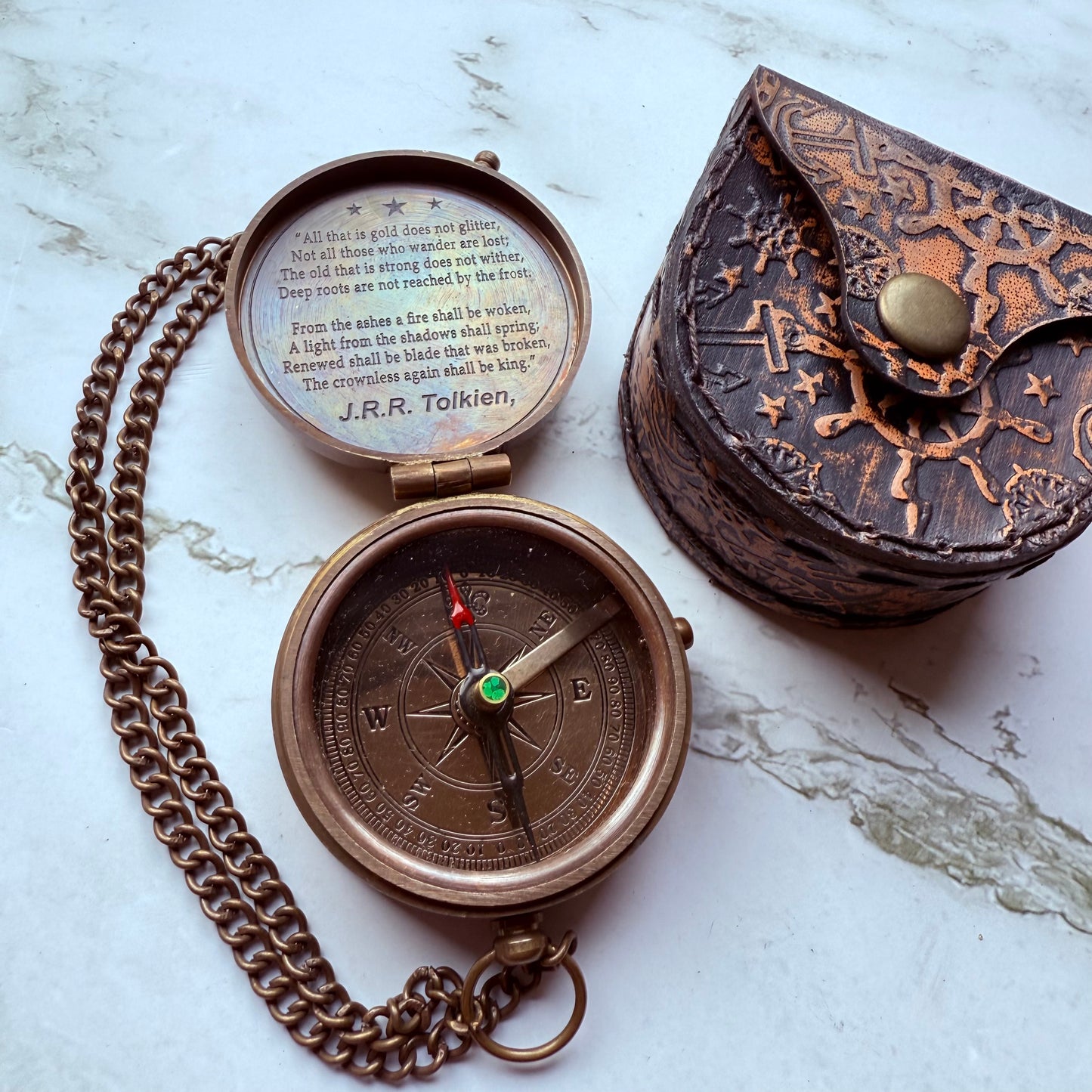 Bronze compass with chain and decorative case on a marble surface