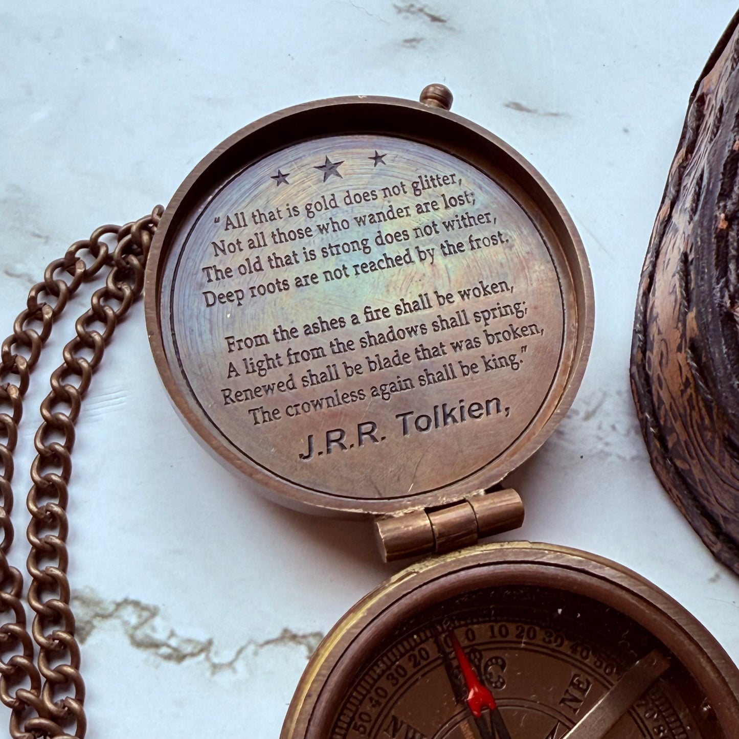 Bronze compass with engraved text on a marble surface