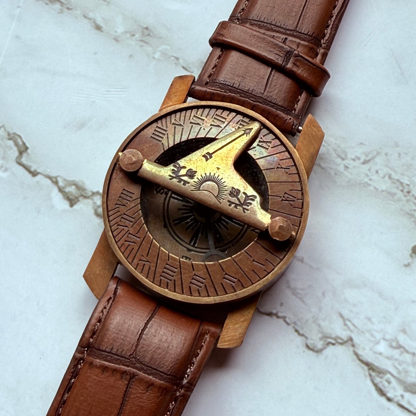 Brown leather sundial compass on a marble surface
