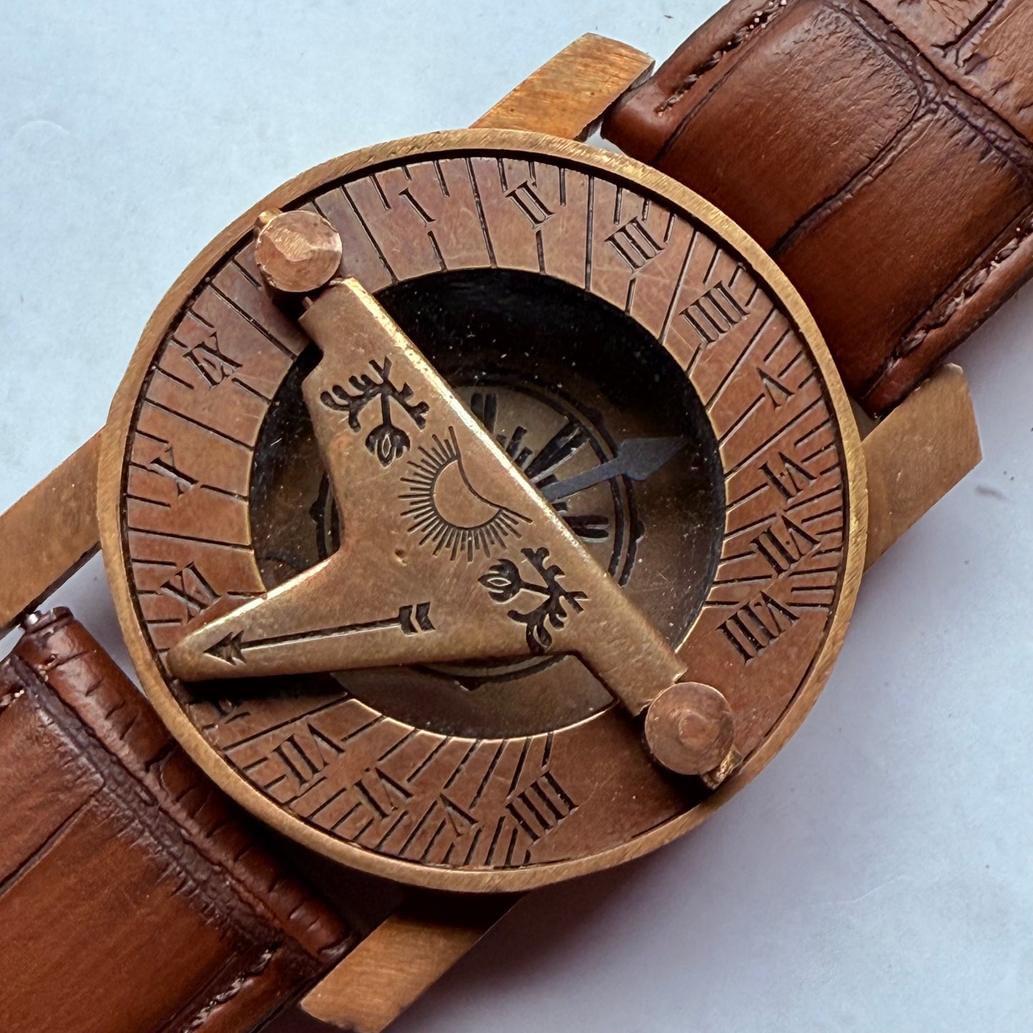 Bronze compass with engraved design on a brown leather strap