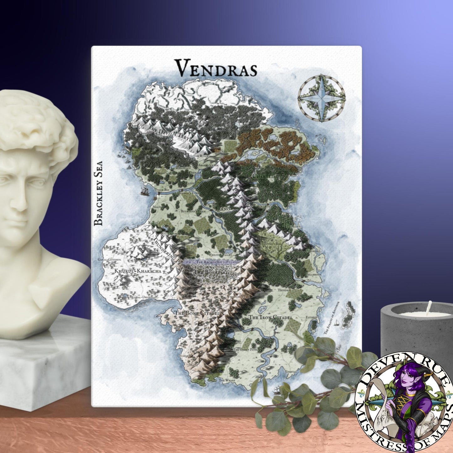 A 18" by 24" canvas print of the Vendras map by Deven Rue sits on a shelf with a stone bust, candle, and greenery.