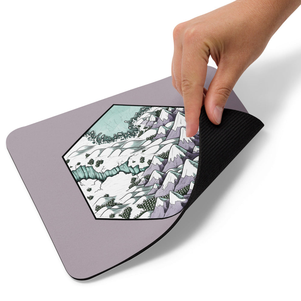 A hand picks up the corner of the Winter's Edge mousepad.