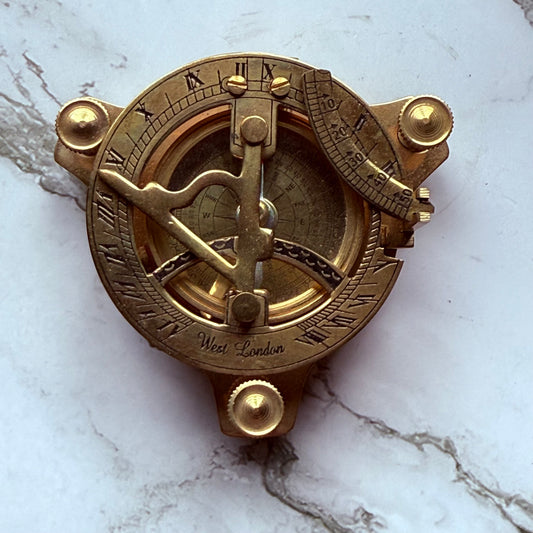 Brass sundial compass on a marble surface