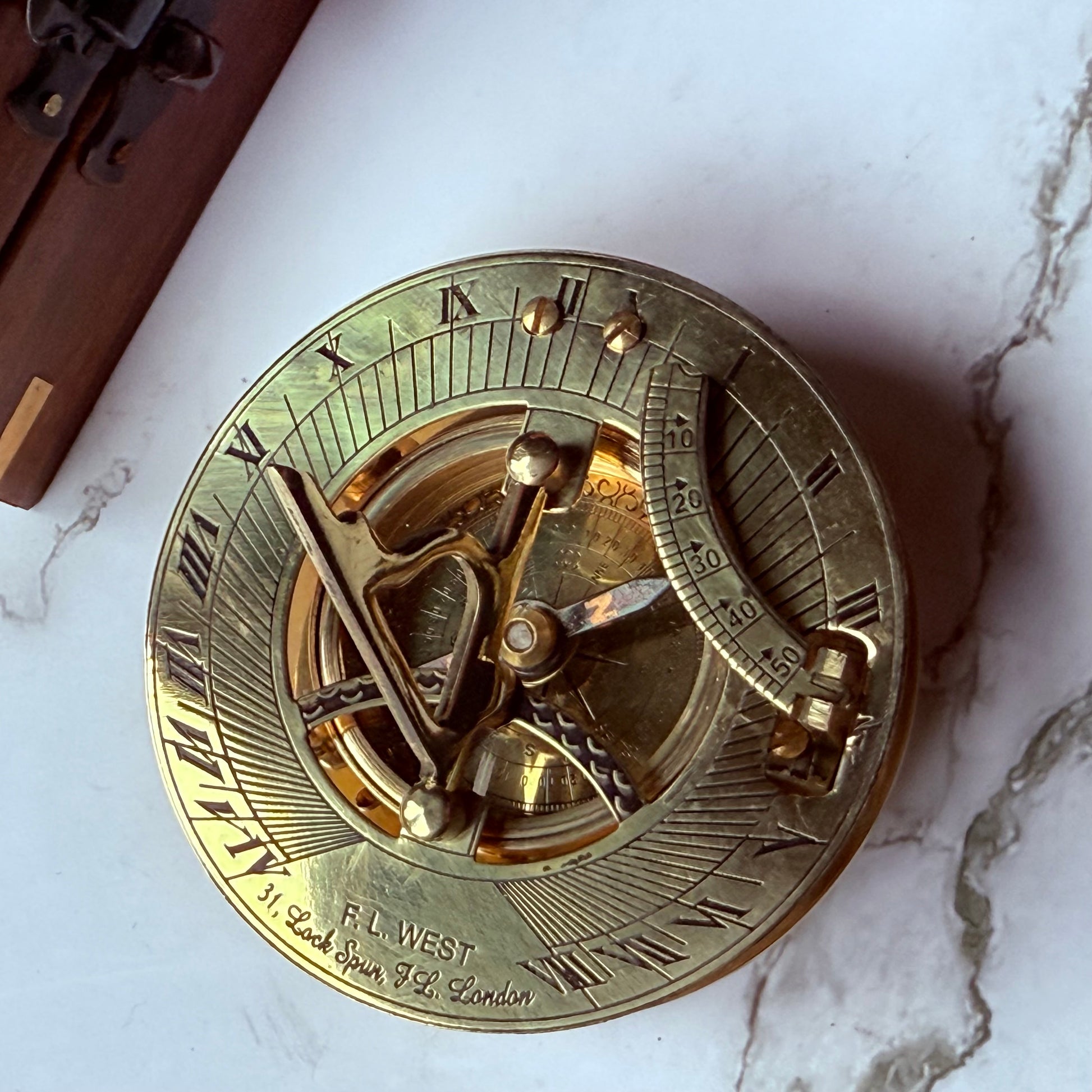 Brass sundial compass on a marble surface