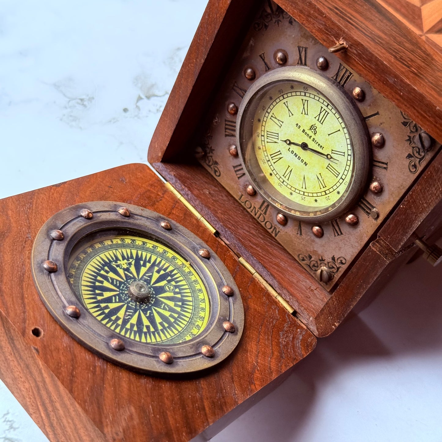 Wooden compass and clock set with brass accents on a light background