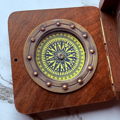 Wooden compass with brass accents on a white background