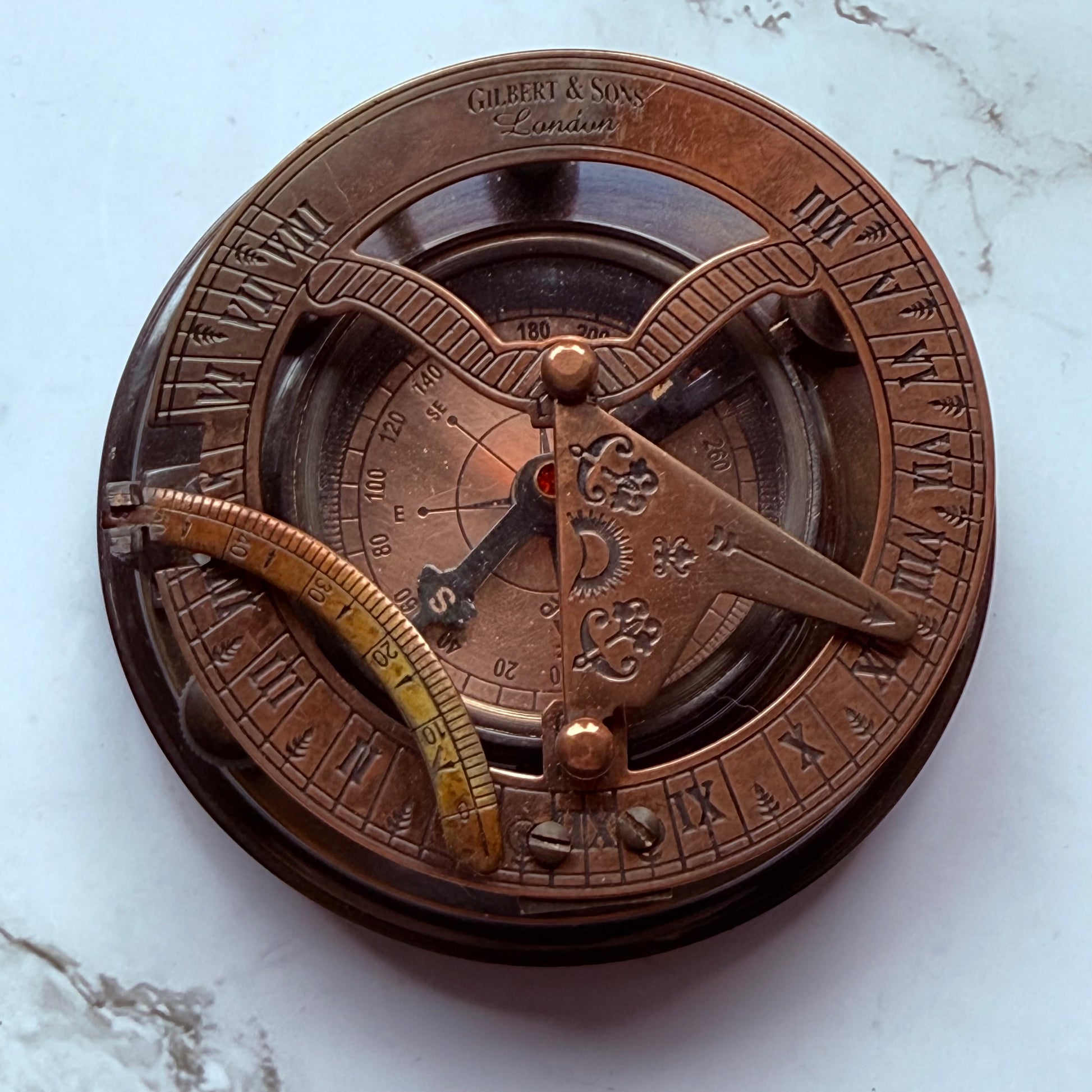 Bronze sundial and compass on a marble surface
