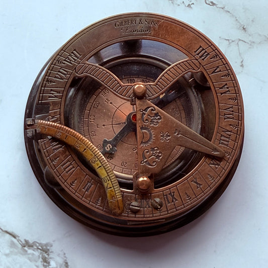 Bronze sundial and compass on a marble surface
