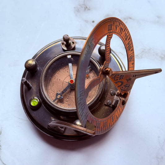 Vintage-style compass with sundial on a marble surface