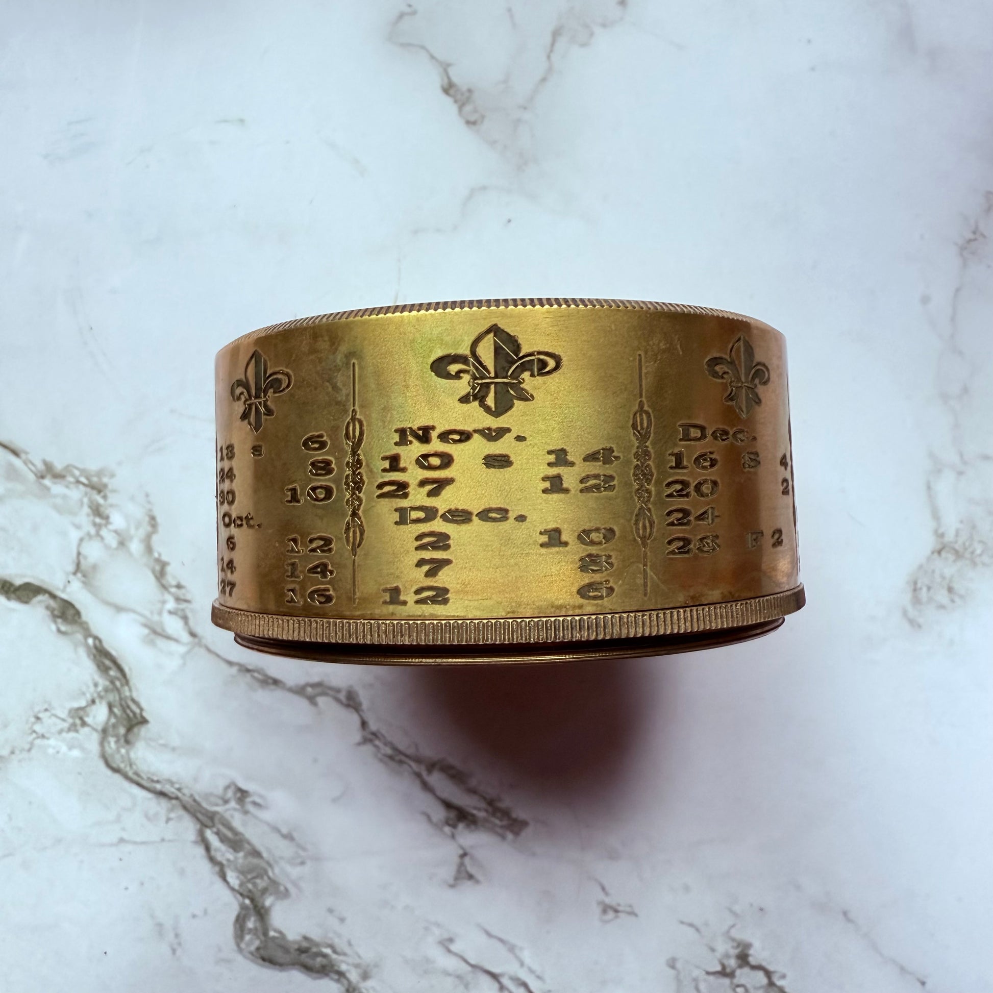 Brass container with engraved numbers and dates on a marble surface