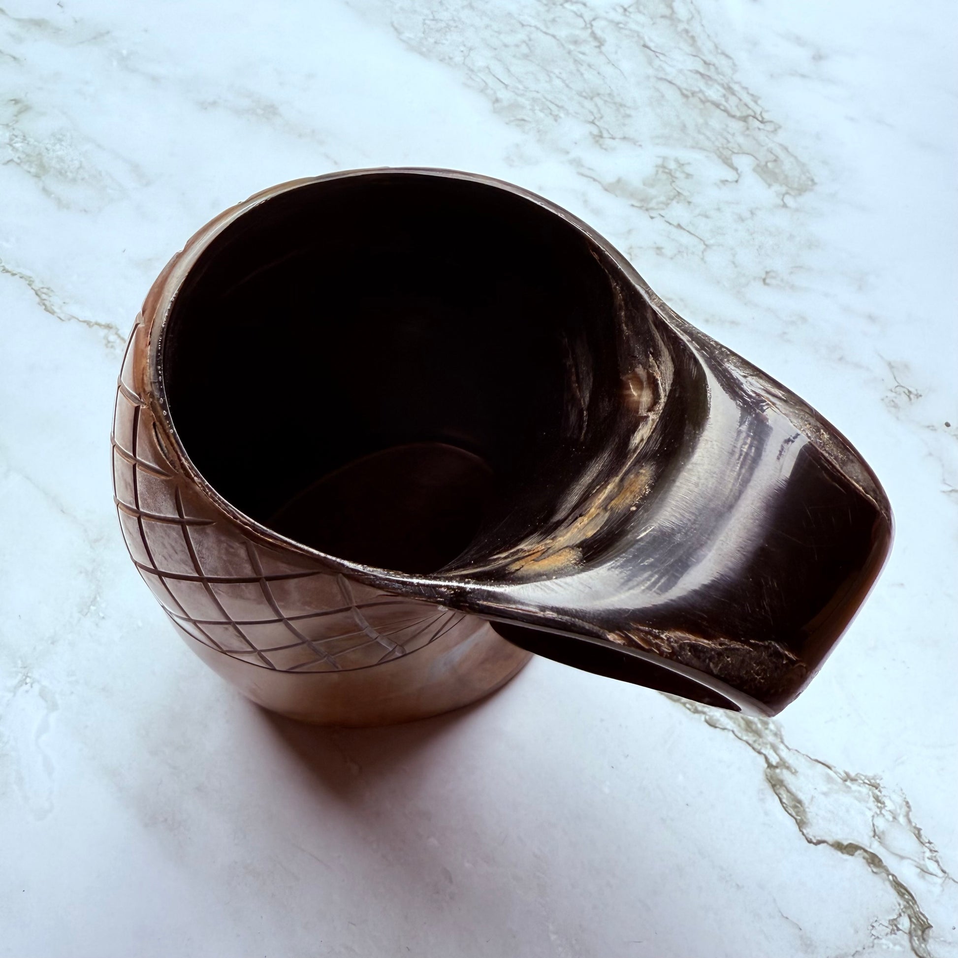 Horn-shaped mug with carved lattice design and curved handle 