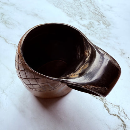 Horn-shaped mug with carved lattice design and curved handle 