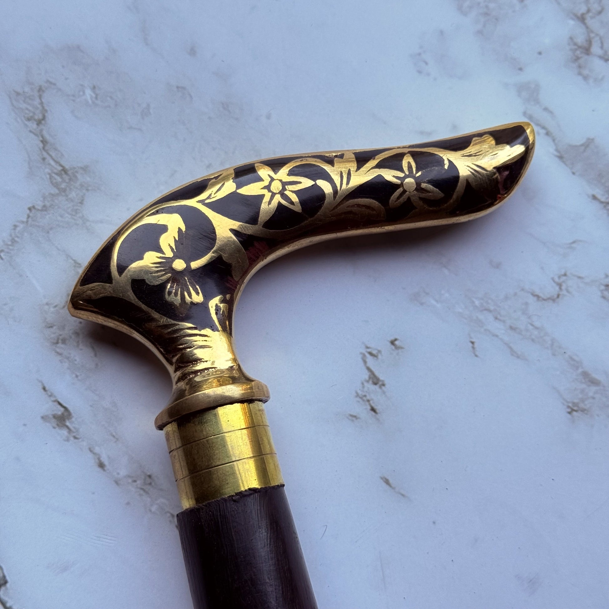 Decorative walking cane handle with brass and black floral pattern
