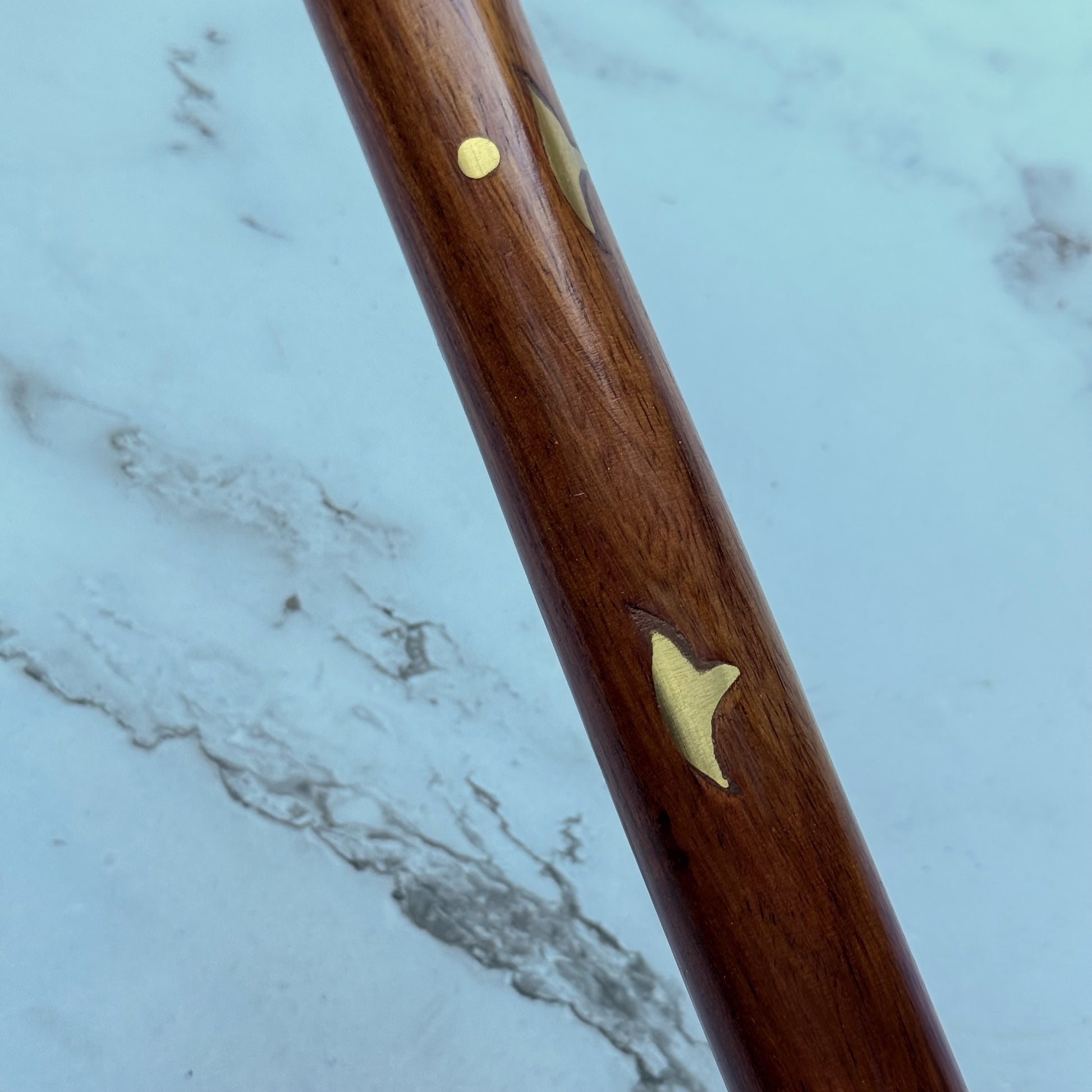 Close up of the wooden cane shaft with brass inlay accents