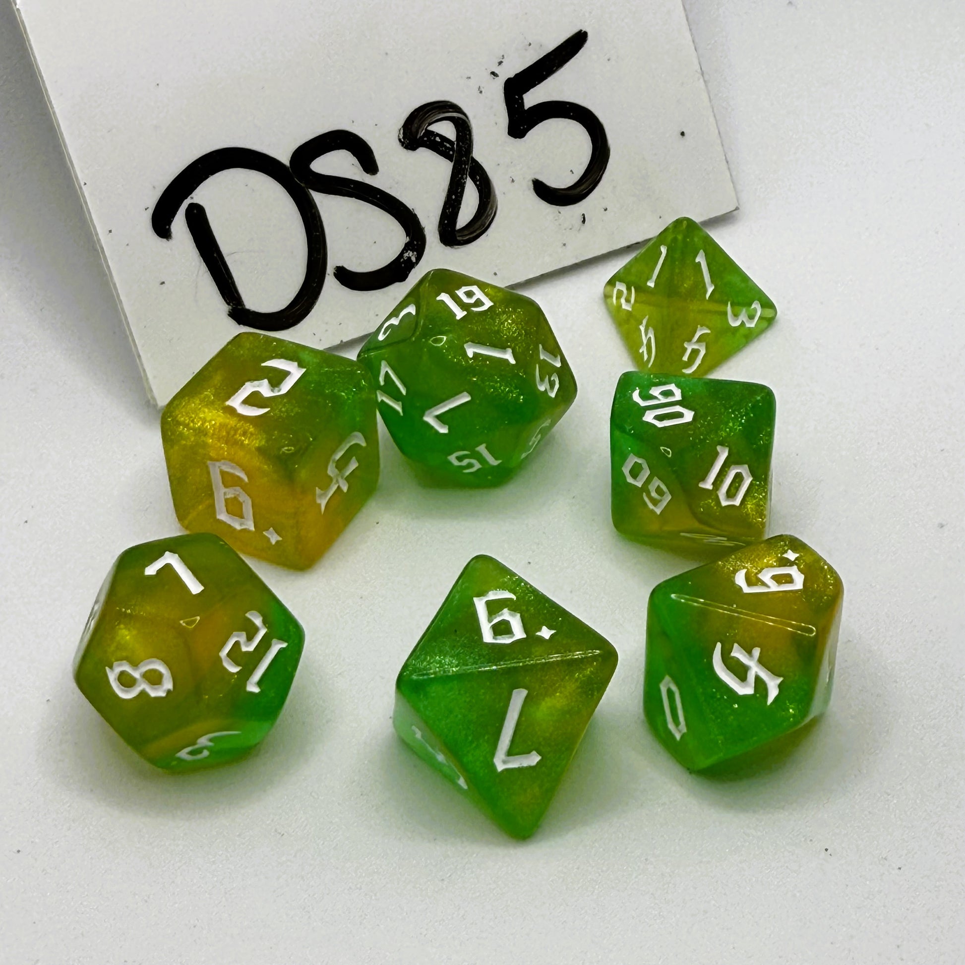 Green and yellow polyhedral dice set with white numbers on a white background, labeled 'DS85'.