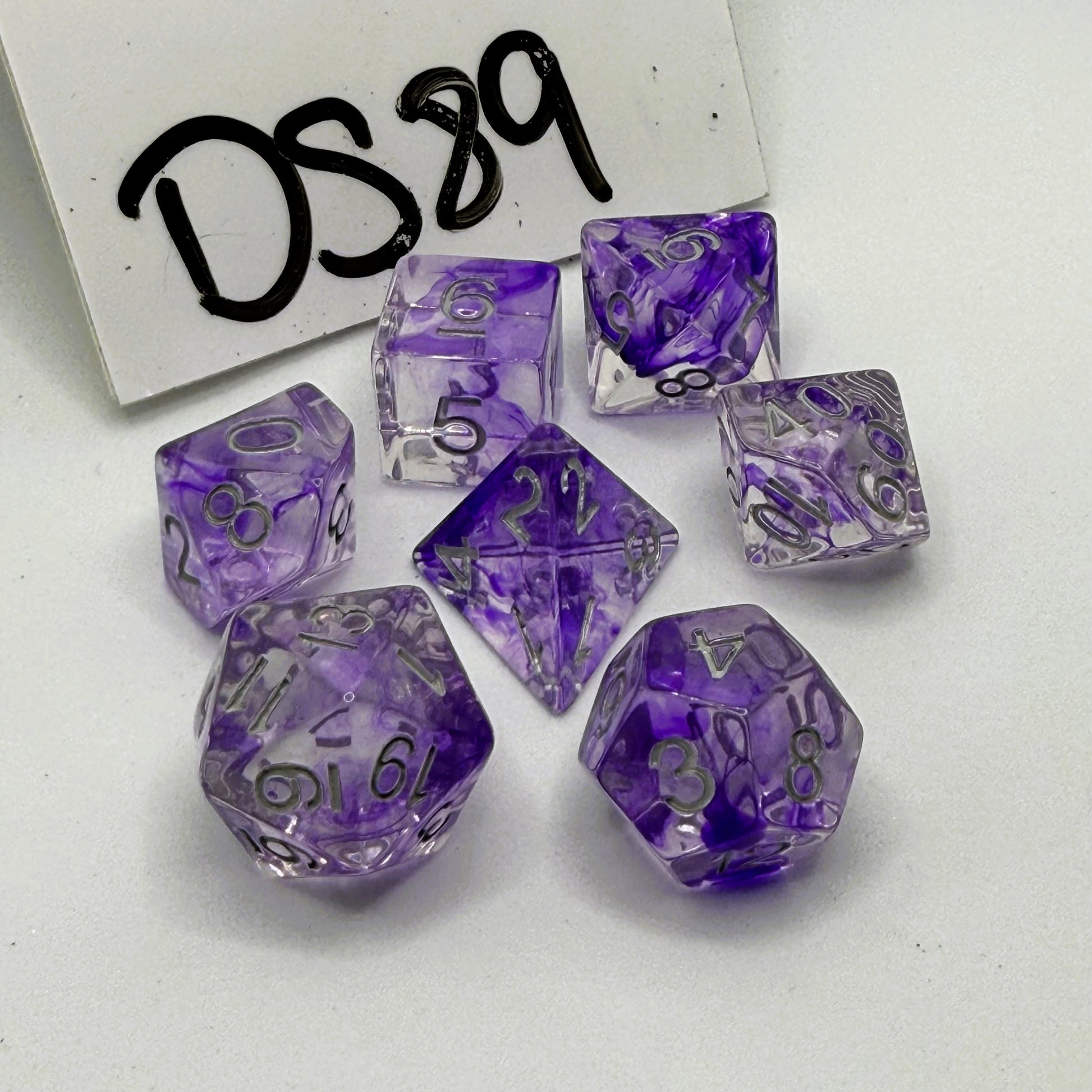 Purple and clear polyhedral dice set on a white background labeled 'DS89'