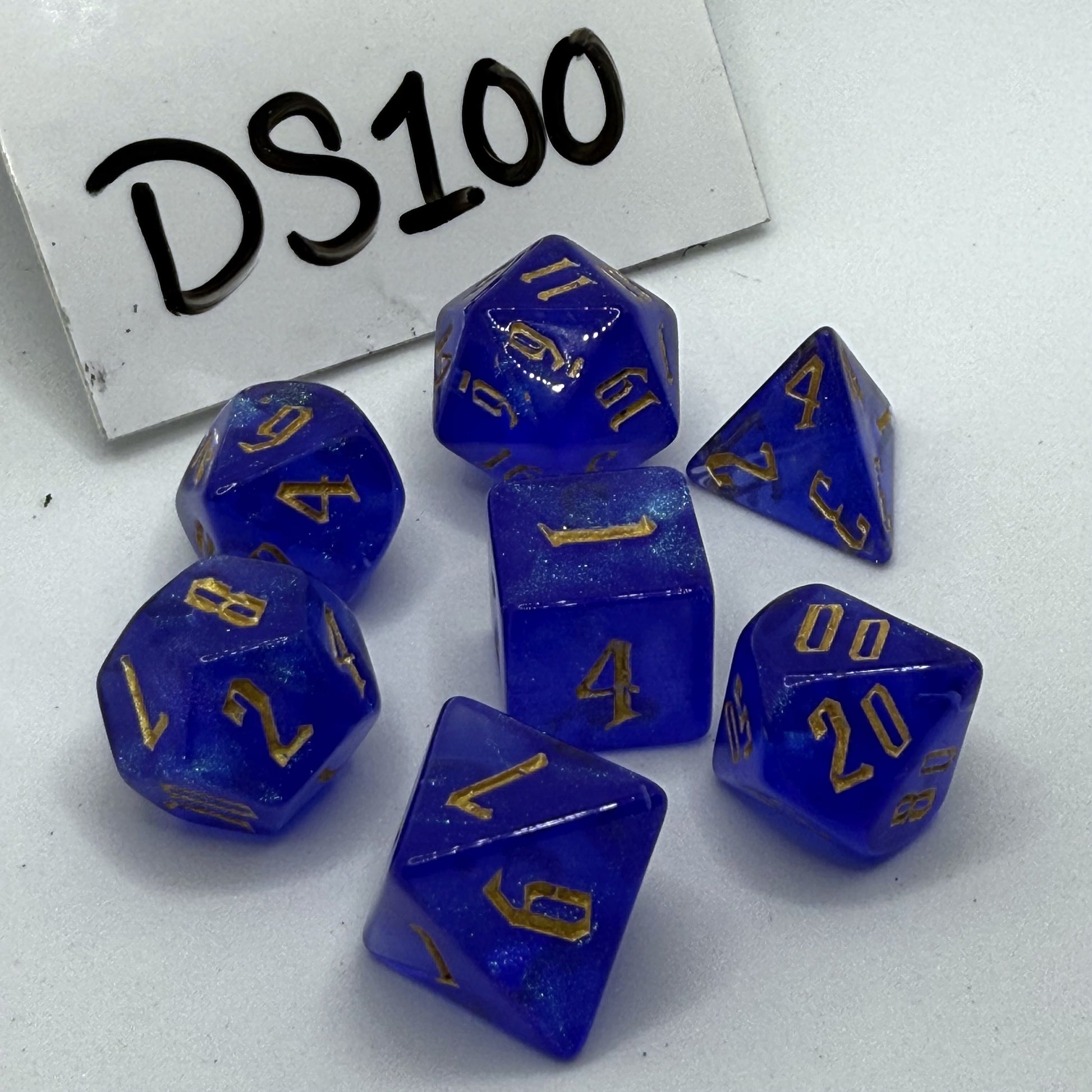 Photo of a set of 7 cobalt blue polyhedral dice with gold numbers.