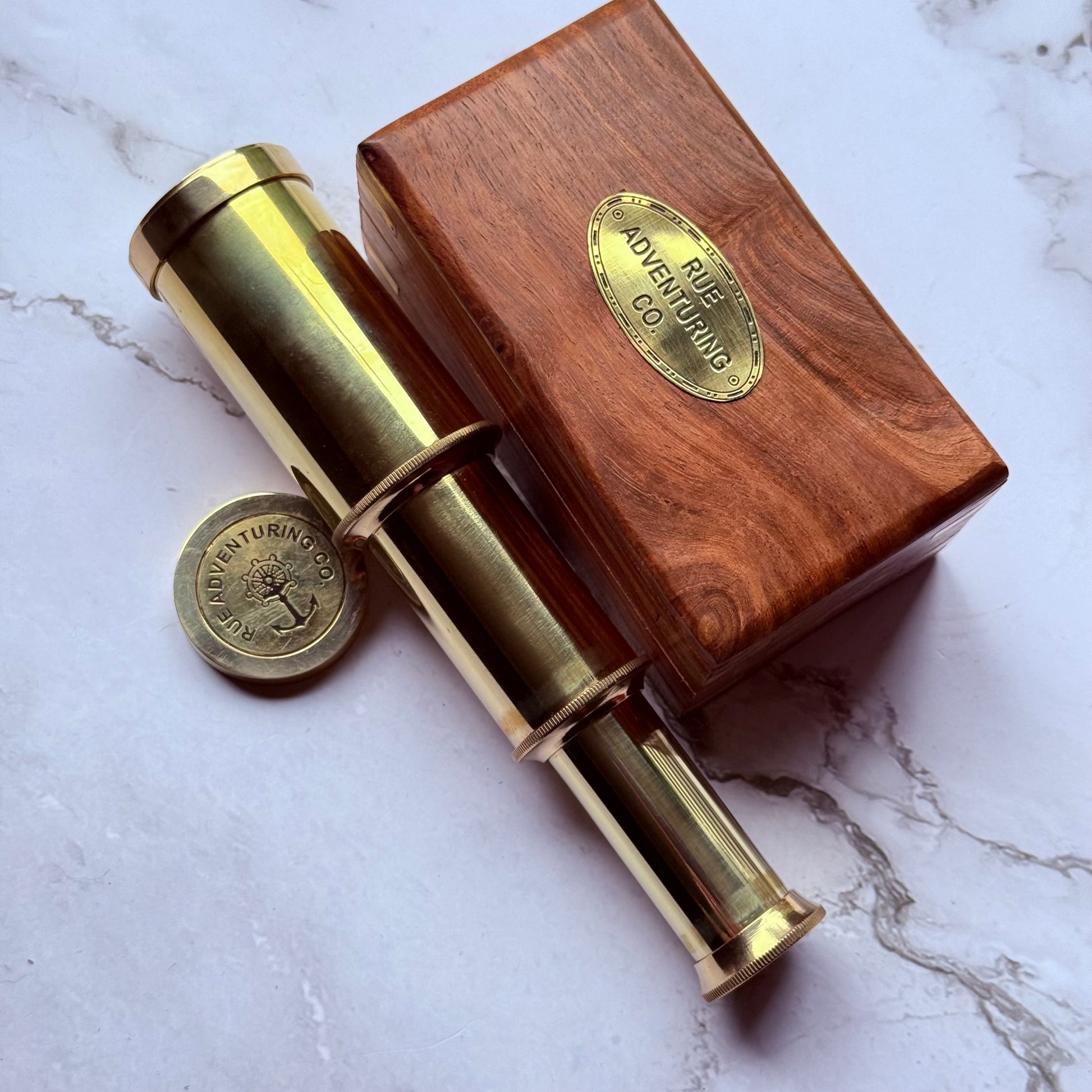 Brass telescope with wooden box on a marble surface