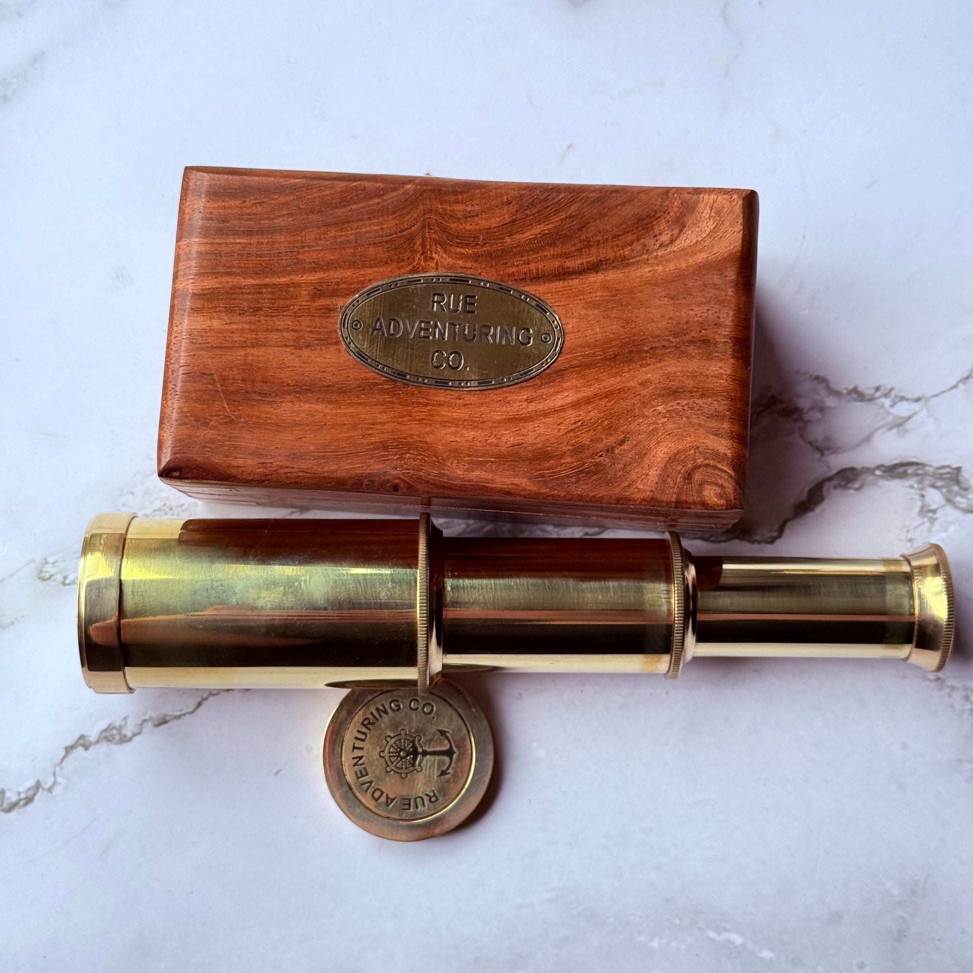 Brass telescope with wooden box on a marble surface