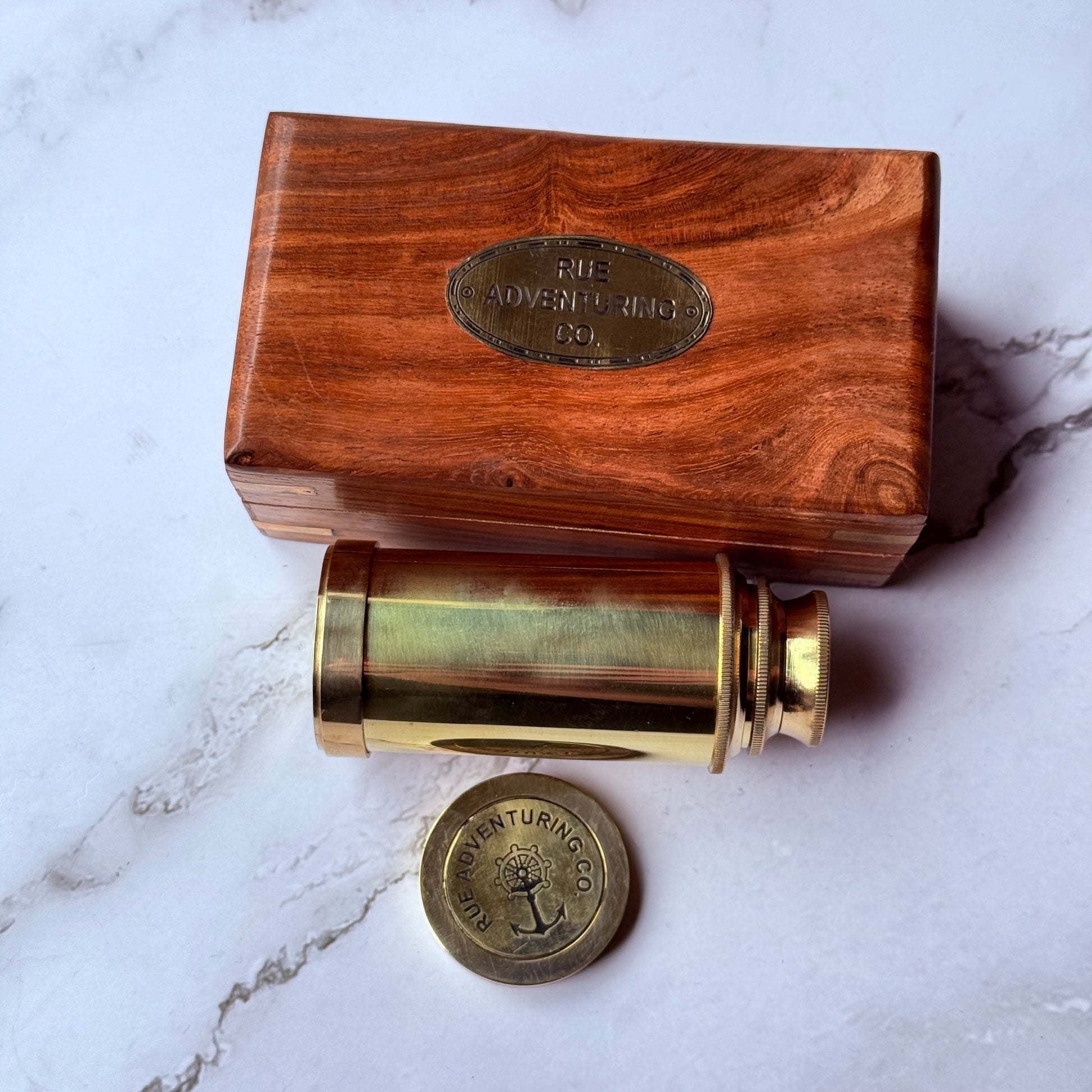 Brass spyglass with wooden box on a marble surface