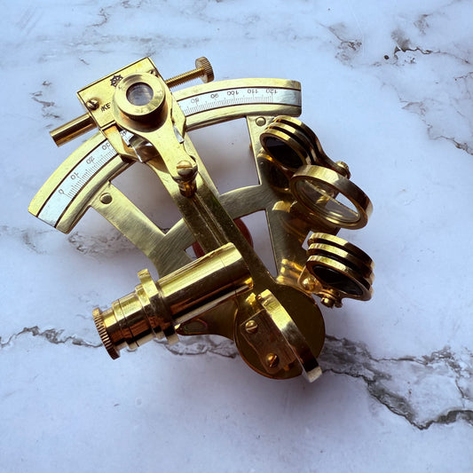 Brass sextant on a marble surface