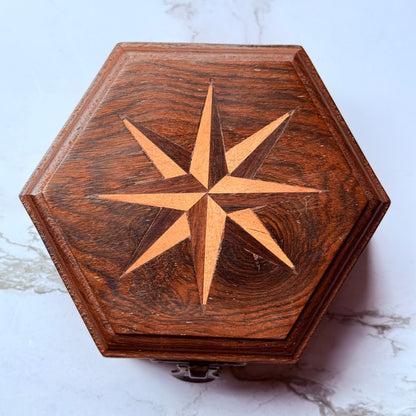 Wooden hexagonal box with star design on a marble surface
