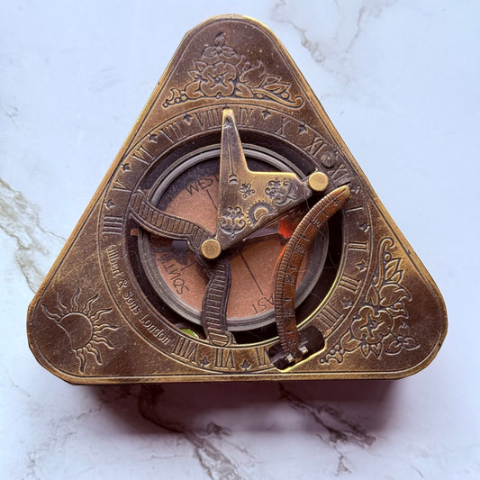 Brass compass sundial on a marble surface