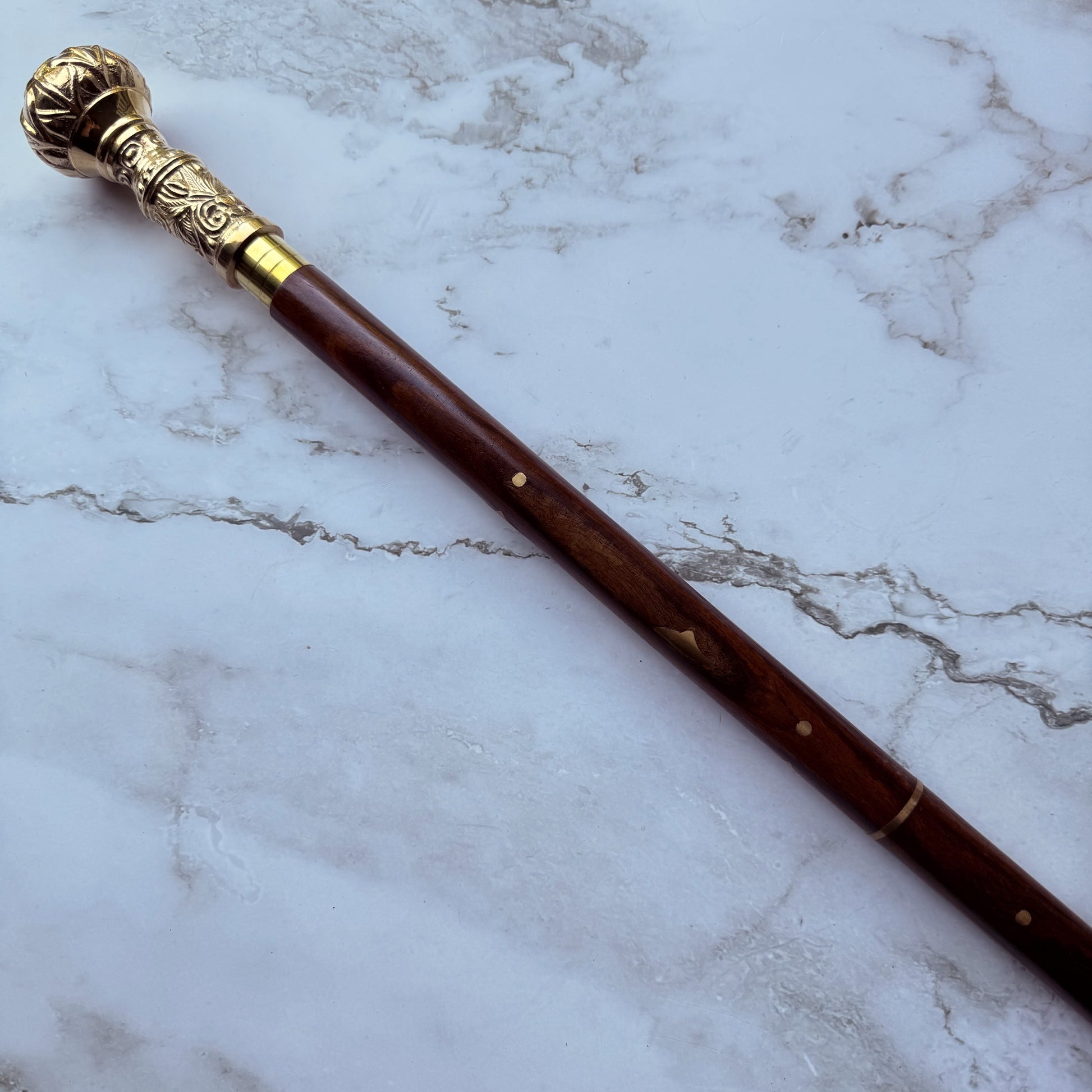 Decorative walking cane with brass top on a marble surface