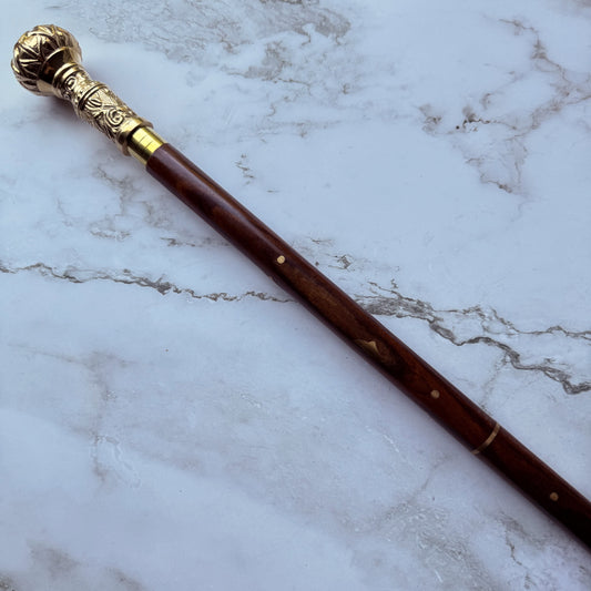 Decorative walking cane with brass top on a marble surface