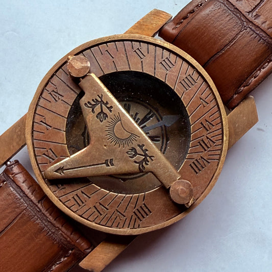 Bronze compass with engraved design on a brown leather strap