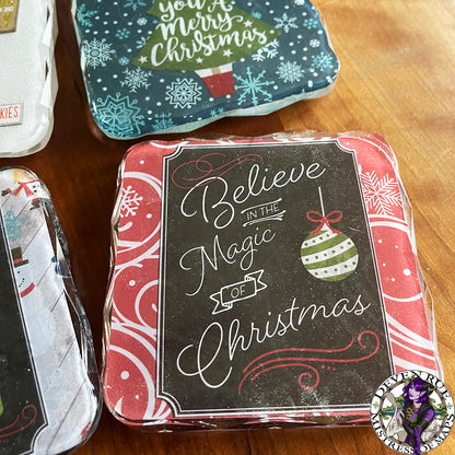 A close up of a resin coaster with red and white decoration, a traditional ornament illustration, and the words "Believe in the magic of Christmas".