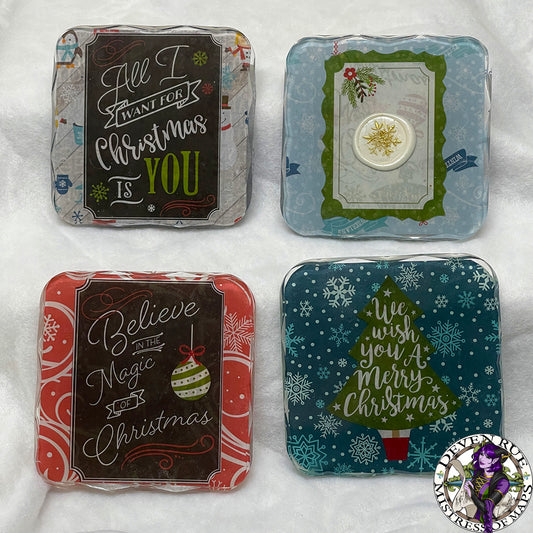 A set of four coasters with Christmas themed decorations - florals, snow, and greenery - in shades of blue, green, red, white, and gold.