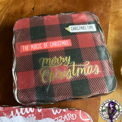A close up of a coaster with red and black flannel with the words "Christmas time", "The magic of Christmas", and "Merry Christmas" on it.