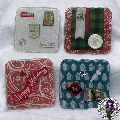 A set of four coasters with winter illustrations like snowflakes, florals, white wax seals with golden gilded snowflakes, and mugs with whipped cream.