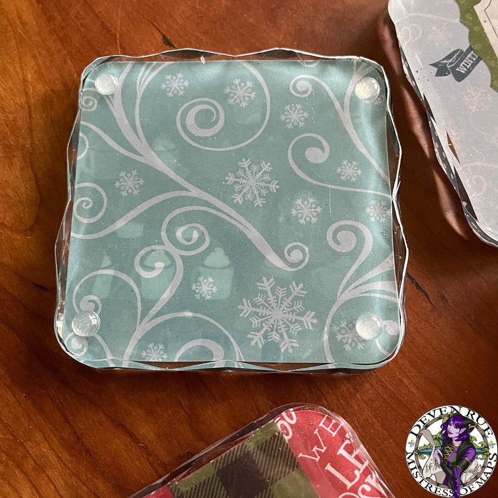 A close up of a resin coaster with ice blue background and white swirls and snowflakes.