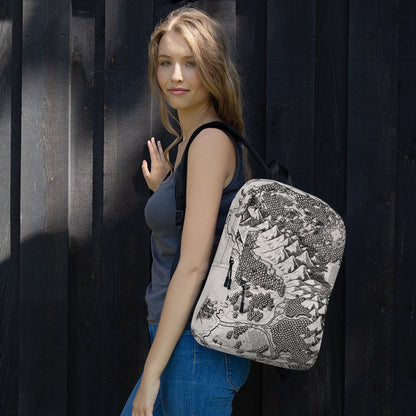 A model wears a backpack with the Arriving at Port map by Deven Rue printed on it over one shoulder.